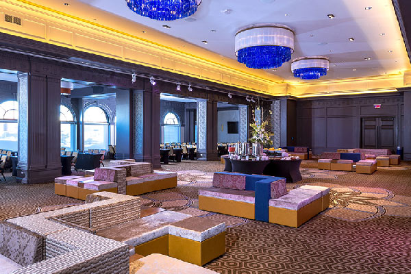 Spacious event lounge with modern seating, large chandeliers, and soft lighting.